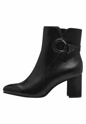 Bottine en cuir noir avec un bout pointu, un accent circulaire sur le côté et un talon épais texturé. Surface lisse avec un minimum de détails.