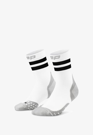 Chaussettes de sport blanches avec deux rayures noires au niveau du revers, bout et talon renforcés en gris, fabriquées à partir d'un tissu texturé et respirant.