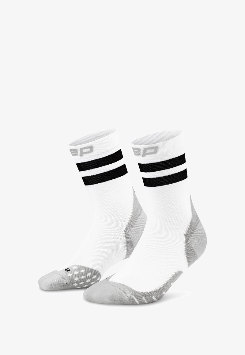 Socks da ginnastica bianchi con due strisce nere in cima, con punta e tallone grigi rinforzati, realizzati in un tessuto testurizzato e traspirante.