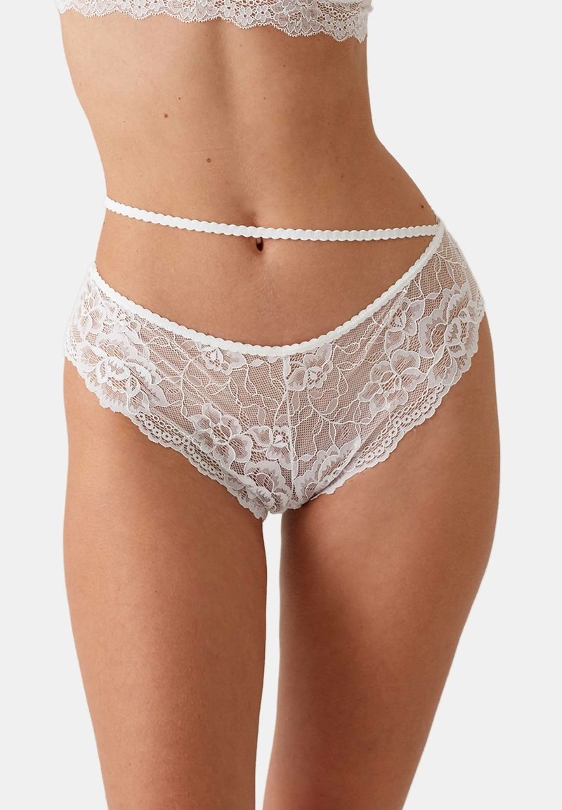 Witte kanten lingerie met bloemenpatronen, golvende randen en een delicate tailleband. Doorzichtige stof met een zachte textuur.