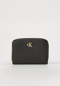 Portefeuille en cuir noir texturé avec quincaillerie dorée, présentant un logo "CK" à l'avant et une fermeture éclair le long du bord supérieur.