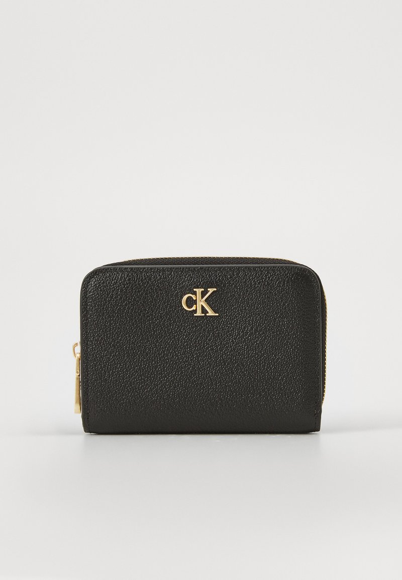 Portefeuille en cuir noir texturé avec quincaillerie dorée, présentant un logo "CK" à l'avant et une fermeture éclair le long du bord supérieur.