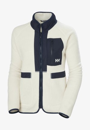 Kurtka polarowa w kremowym kolorze z granatowymi akcentami. Posiada wysoki kołnierz, zasuwaną kieszeń na piersi oraz dwie kieszenie z przodu. Widoczne kontrastowe szwy.