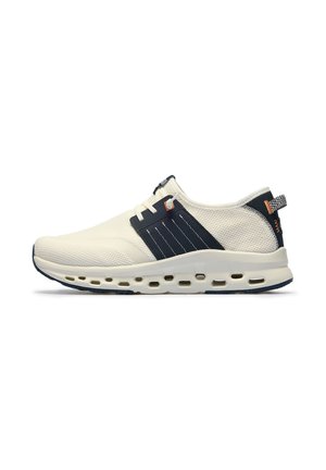 Zapatilla deportiva blanca de malla con panel lateral negro, suela ventilada, cordones blancos y lengüeta trasera estampada, vista lateral sobre fondo blanco.