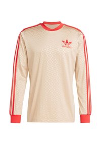 Gaiši brūns krekls ar garām piedurknēm, ar ģeometrisku rakstu, sarkaniem svītrām uz piedurknēm un izšūtu adidas logo kreisajā krūtī.