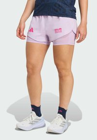 Lichtpaarse sportshorts met een interne voering, een roze "BMW Berlin Marathon" logo en drie-strepen accenten. Witte sneakers met grijze details.