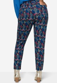 Pantaloni affusolati con stampa astratta multicolore che presenta motivi blu, rosa e neri, con una texture liscia e tasche laterali.