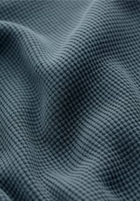 Tessuto di un blu scuro e strutturato con un motivo a nido d'ape, caratterizzato da una superficie morbida e traspirante e un aspetto tridimensionale.