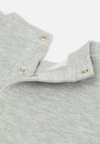 Collo di camicia in cotone grigio con bottoni a scatto, caratterizzato da una texture a coste e un morbido rivestimento interno. Dettaglio ravvicinato del tessuto.