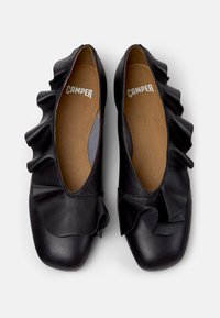 Zwarte leren platte schoenen met geplooide accenten bij de opening, een afgeronde neus en een gladde textuur. De binnenkant is beige met zichtbare "CAMPE" branding.