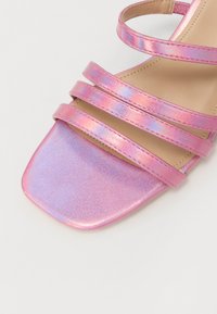 Sandal cu toc drept, metalizată roz, cu trei bretele orizontale și un suprafață texturată netedă.