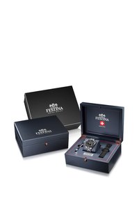 Festina Šveicarijos laikrodis tamsiai mėlyname dėžutėje su raudonomis detalėmis. Pridedamas metalinis apyrankė ir odinė dirželis. Dėžutėje yra logotipas tiek išorėje, tiek viduje.