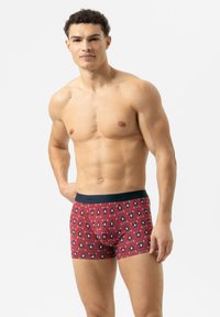 Caleçons boxers rouges avec un motif de pingouins, taille élasticisée noire, et en tissu doux et extensible. Le design présente des graphiques de pingouins au style ludique et cartoon.