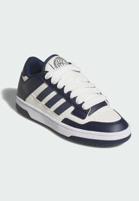 Biele a námornícke nízke tenisky s tromi bielymi pruhmi, polstrovaným jazykom, textúrovaným koženým zvrškom a gumovou podrážkou. Okrúhla špička s perforáciou.