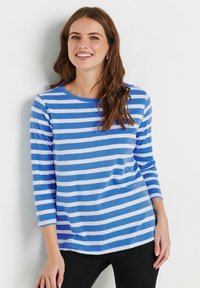 Blau-weiß gestreiftes Longsleeve-Shirt mit rundem Halsausschnitt, weichem Material und lässiger Passform, kombiniert mit schwarzen Hosen.