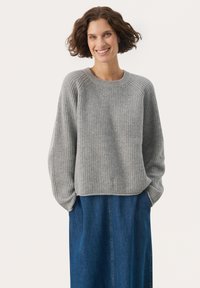 Grau gerippter Strickpullover mit Rundhalsausschnitt und langen Ärmeln, kombiniert mit einem blauen Jeansrock. Der Stoff hat eine weiche Textur.