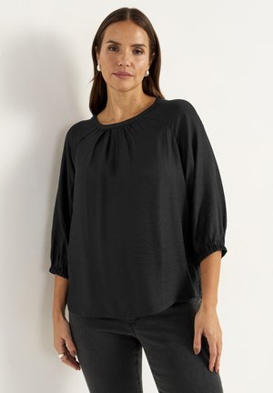 Sort bluse med rund halsudskæring, trekvart puffærmer og rynket detaljering ved halsudskæringen; lavet af blødt, let stof.