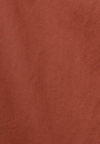 Tissu texturé de couleur terre cuite chaude, avec un motif subtil de tissage diagonal, créant un aspect lisse mais durable.