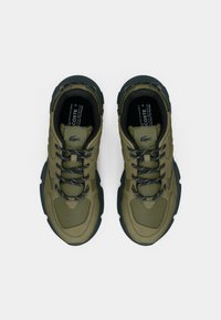 Olive green athletic shoes with textured fabric, black accents, and sturdy soles. Features round laces and logo detail on the tongue.