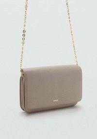 Borsa a tracolla in pelle taupe con catena dorata e piccolo logo dorato "MNG" sulla chiusura a patta anteriore.