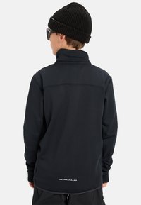 Czarny polar z długim rękawem i wysokim kołnierzem, z teksturowanej tkaniny, płaskimi szwami oraz dekoracyjnym trójkątnym wzorem na końcu.