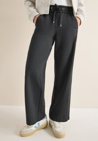 Zwarte, ruime sweatpants met een elastische tailleband en een trekkoord. Gave textuur met zijzakken en contrasterende stiksels.