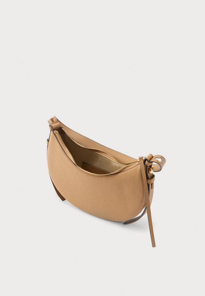 Καφέ τσάντα χειρός σε σχήμα ημισελήνου από δέρμα με χρυστό φερμουάρ και ρυθμιζόμενο ιμάντα, εμφανιζόμενη ανοιχτή σε λευκό φόντο.