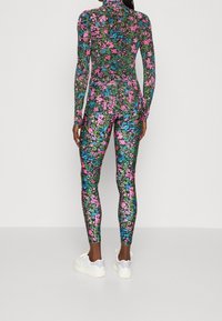 Langærmet bodysuit lavet af strækstof, med et blomster mønster i pink, blå og grøn på en sort baggrund. Tætsiddende design.