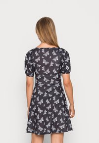 Vestido preto com padrão de borboletas brancas, mangas curtas bufantes, corpete ajustado e saia rodada. Tecido suave com um brilho sutil.