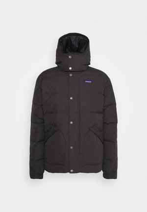 Chaqueta de plumas negra con cuello alto, cierre de botones a presión, dos bolsillos laterales y una textura suave. Logo de Patagonia en el pecho.