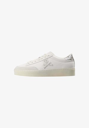 Zapatilla blanca de corte bajo con diseño de cordones, emblema de calavera y huesos cruzados en el lateral, y acento de talón texturizado en plata.