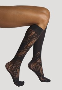 Calze nere fino al ginocchio con un design a rete trasparente e a motivo. Presentano una fascia superiore nera solida e texture intricate intrecciate.