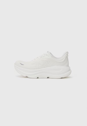 Baskets blanches avec une semelle rembourrée, une tige texturée et un orteil renforcé. Comprend un logo bien visible sur le côté et un design épuré.