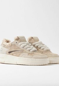 Sneaker in suede beige presentano suole in gomma bianca spessa, lacci cremosi e soffici, e un rivestimento testurizzato. Il design include una discreta striscia laterale.