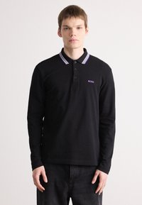 Polo shirt preto de mangas longas com gola cinza em contraste e riscas roxas. Logotipo "BOSS" bordado no peito. Material de algodão.