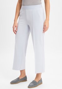 Lichtgrijze, stretchstof broek met een platte tailleband, brede pijpen en subtiele zijnahts, gecombineerd met grijze instapschoenen.