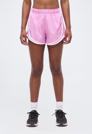 Personne debout portant un short de sport rose, des chaussettes blanches montantes et des chaussures de course noires avec des semelles rose clair.