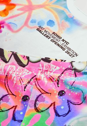 Farbiger T-Shirt aus weichem Stoff, mit einem Blumenmuster in Rosa- und Blautönen und einem Text über eine Kunstausstellung.