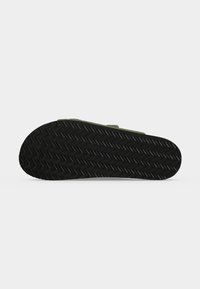 Μαύρη λαστιχένια σόλα σανδαλιού με σχέδιο ζιγκ-ζαγκ, απεικονίζεται σε απλό λευκό φόντο.