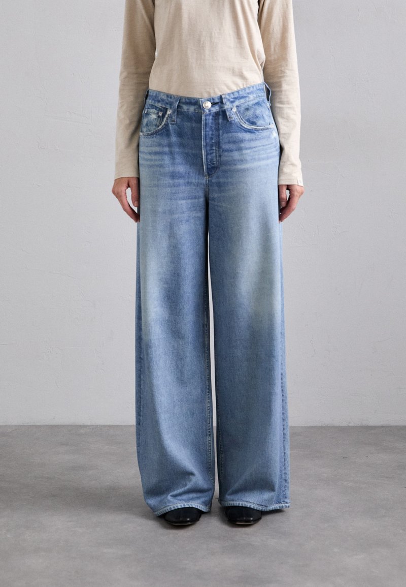 Light blue wide-leg denim jeans with a faded wash, front pockets, and a button closure. Paired with a long-sleeve beige top.