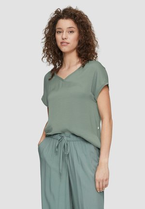 T-shirt à col en V à manches courtes en tissu vert muted, associé à un pantalon à taille élastique assorti, offrant une coupe décontractée et une texture lisse.