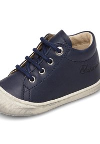 Námořnické kožené vysoké tenisky s bílou gumovou podešví, které mají kulaté kovové kování a námořnické tkaničky. Logo je embosováno na boku.