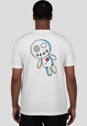 Camiseta blanca con un gráfico colorido de una muñeca estilizada con cabeza de calavera y un diseño de corazón en la parte posterior. Mangas cortas, tejido suave.