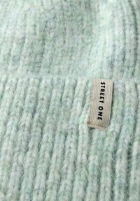 Dziergana czapka z miękkiej, teksturowanej przędzy, w kolorach jasnej zieleni i bieli; zawiera metkę z napisem "STREET ONE" w kolorze czarnym.