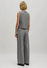 Graues ärmelloses Oberteil mit geradem Schnitt und passenden weiten Hosen, aus strukturiertem Stoff, sichtbaren Nähdetails und minimalistischem Design.