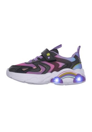 Zapatilla con tela multicolor en morado, rosa y negro. Presenta una correa de velcro y un detalle de arcoíris iluminado en la suela. Suela blanca gruesa.