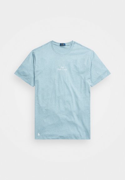 Gaiši zils kokvilnas T krekls ar īsajām piedurknēm, apaļu kaklu un izšūtu "Polo Ralph Lauren" logotipu uz krūtīm. Mīksts, ikdienišķs dizains.