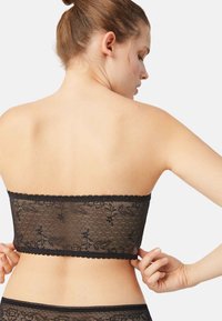 Top bandeau negro sin tirantes de encaje con estampado floral, textura transparente, bordes de encaje con borde festoneado y diseño ajustado. Detalle trasero ajustable.