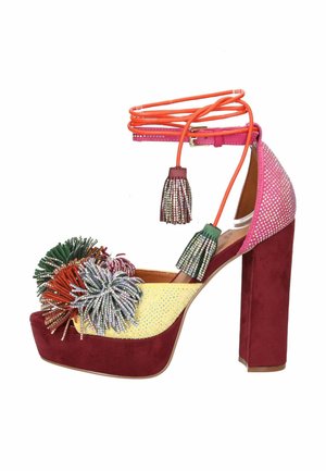 Sandalo platform con tacco alto in suede bordeaux, decorazioni con strass gialli e rosa, pon pon multicolori e lacci arancioni alla caviglia con nappine.