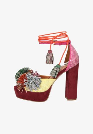 Sandalo platform con tacco alto in suede bordeaux, decorazioni con strass gialli e rosa, pon pon multicolori e lacci arancioni alla caviglia con nappine.